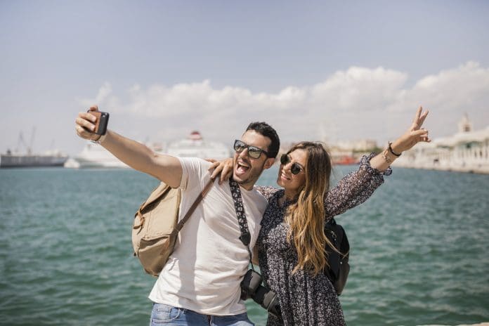 woman-making-peace-sign-with-her-boyfriend-taking-selfie-mobile Preço redefine escolhas de viagem e impulsiona destinos alternativos no Brasil